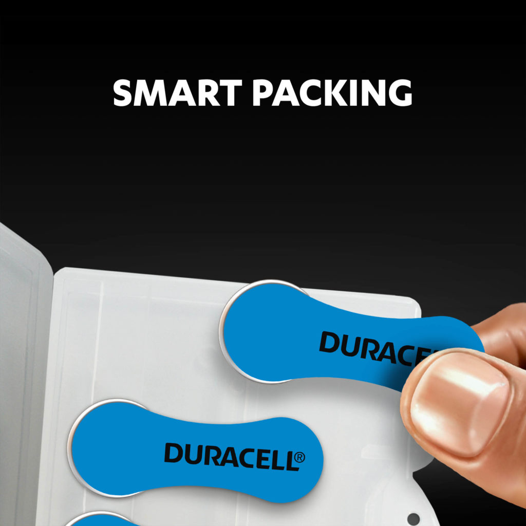 Fingers holding the hearing aids batteries from a smart package
